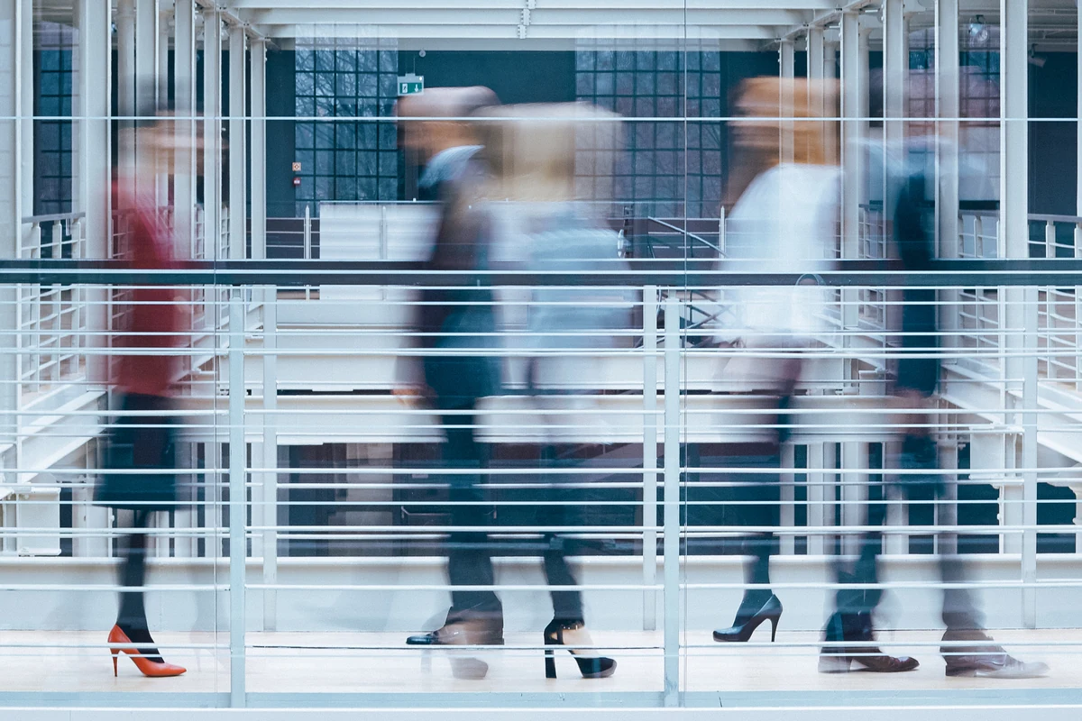 People moving through a bright contemporary office atrium.
